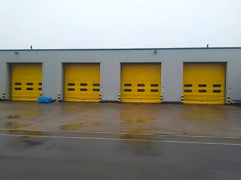 Four hi-speed industrial roll up doors with yellow coating finish in-situ at a warehouse